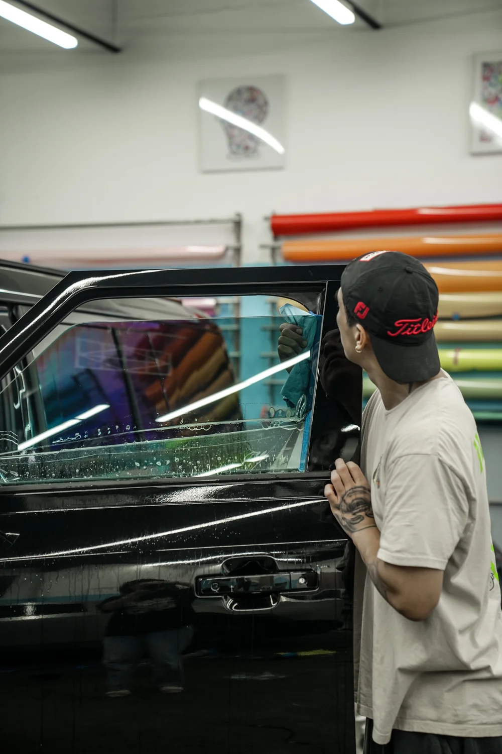 Installer working at the upper corner of a wet Defender door window with a blue cloth beside the black door frame