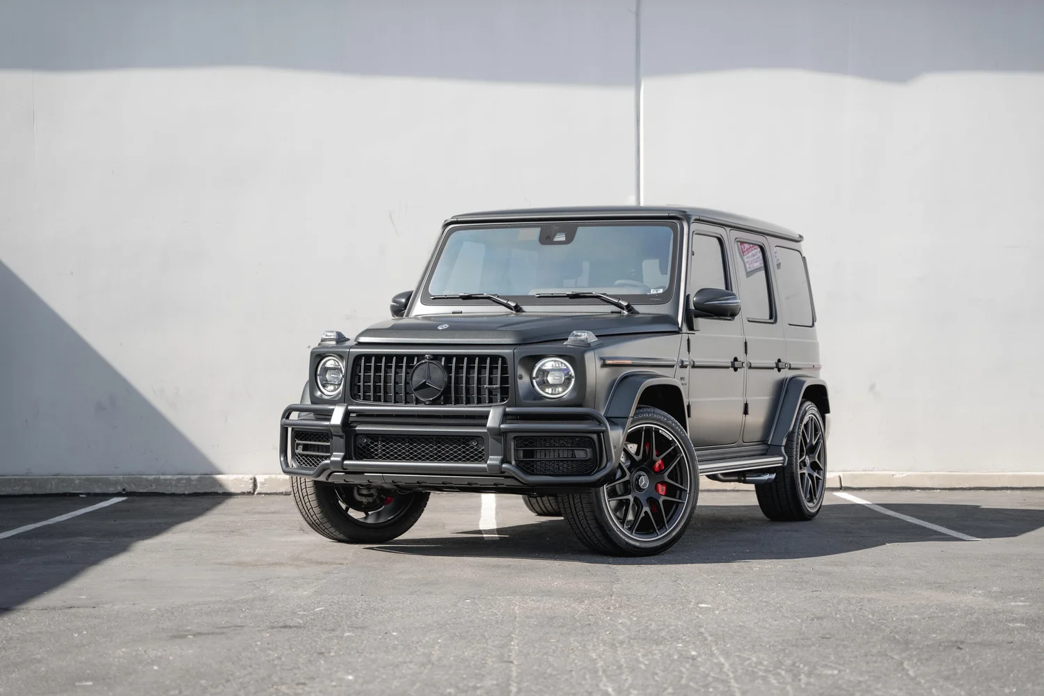 Landscape front-three-quarter view of the complete charcoal-grey G 63 with dark wheels, red calipers and a vertical-bar grille