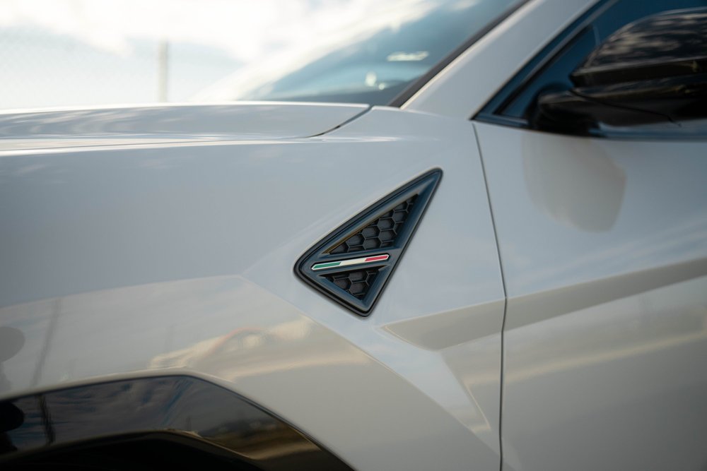 Lamborghini Urus with Chalk vinyl wrap, triangular fender vent with a tricolor badge beside the mirror