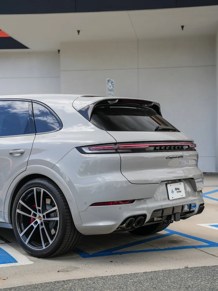 Rear three-quarter detail of the light grey Porsche Cayenne GTS, with its light bar, diffuser and four exhaust tips.