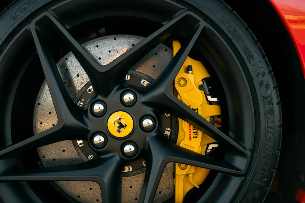 Black Ferrari F8 wheel with yellow brake caliper and drilled brake disc