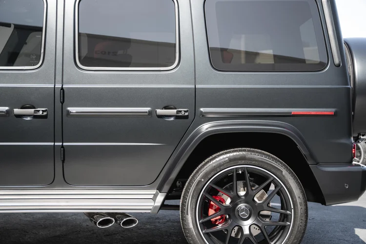 Side-body detail of the grey G 63 with a dark rear wheel, red caliper, silver running board and twin exhaust tips