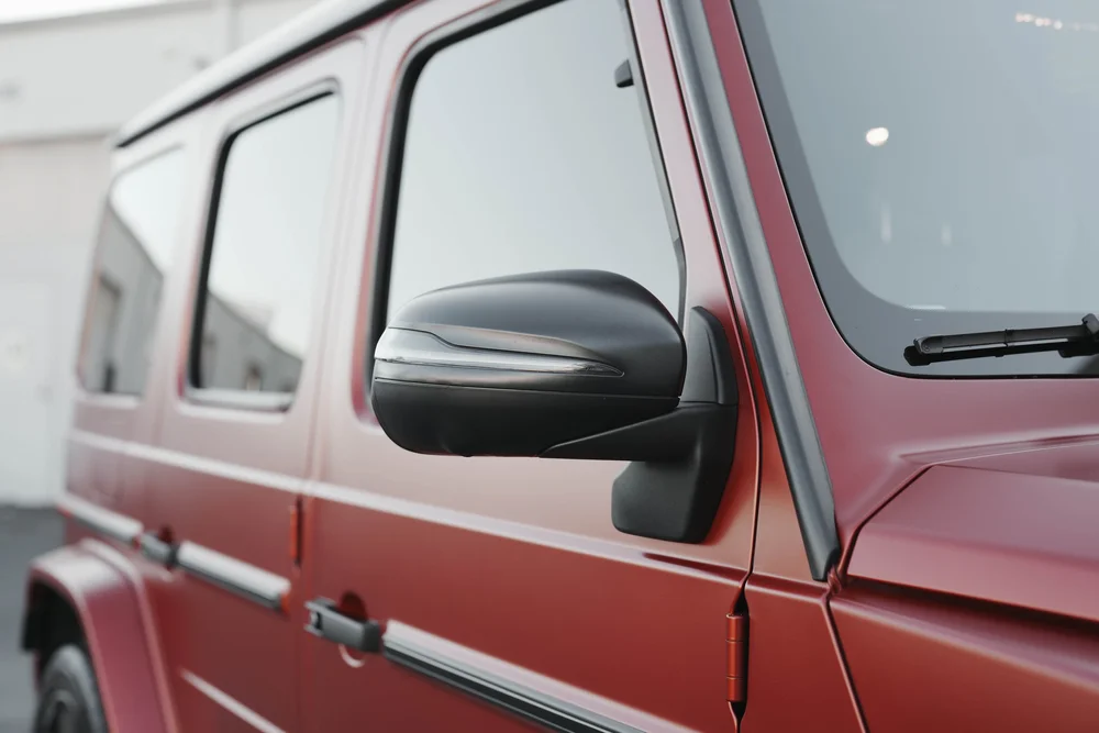G63 black side mirror and dark side glass above matte red doors with external hinges and black trim