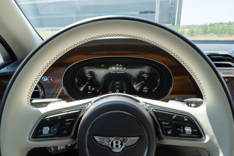 Cream-colored Bentley steering wheel in front of the instrument display.