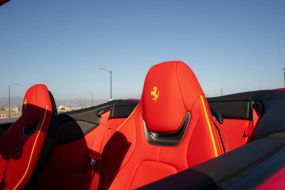 Red Ferrari Portofino seats with yellow embroidered horses and yellow piping against the open sky