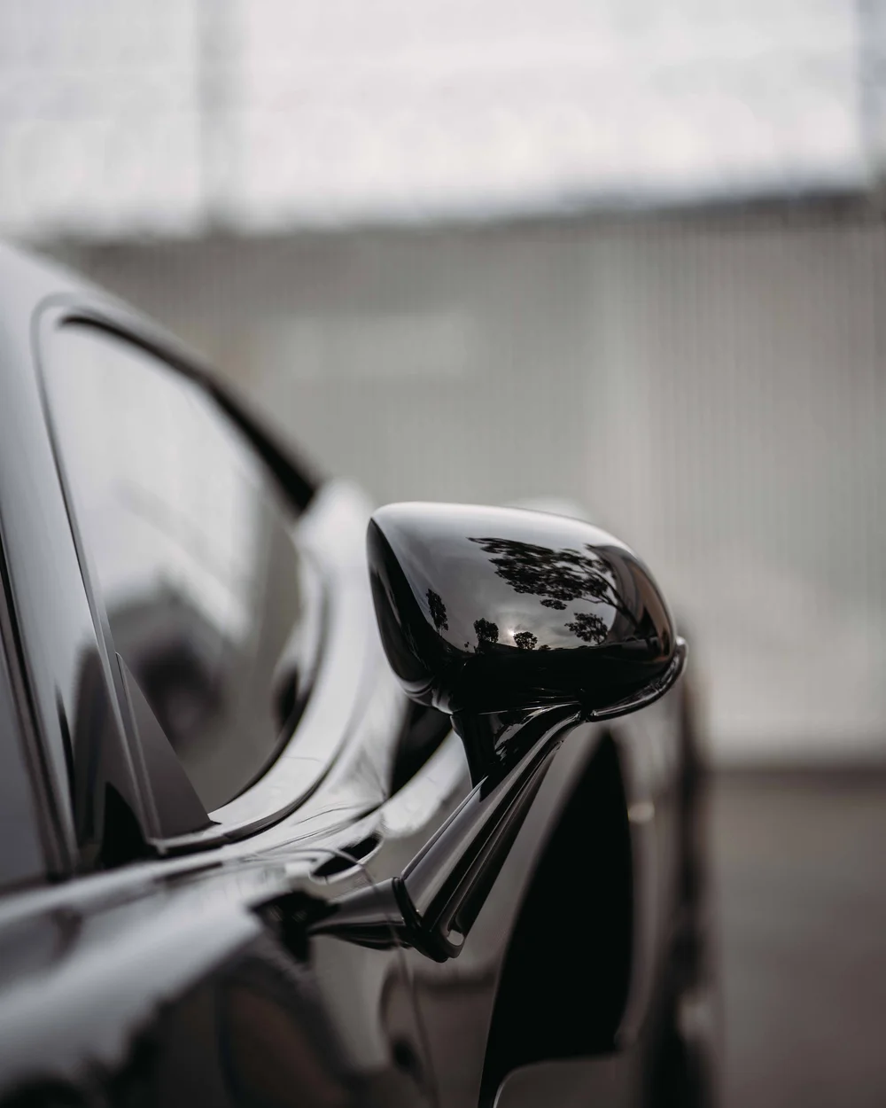 Glossy dark mirror reflecting trees beside the McLaren's side window.