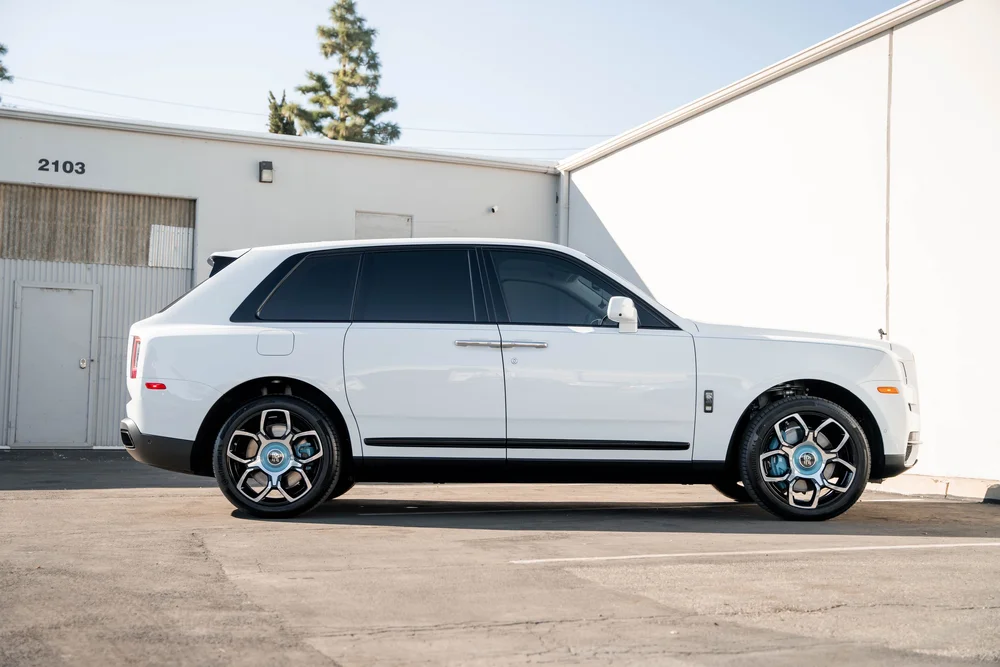 White Rolls-Royce Cullinan — full side profile with white bodywork, dark glass and turquoise wheel accents