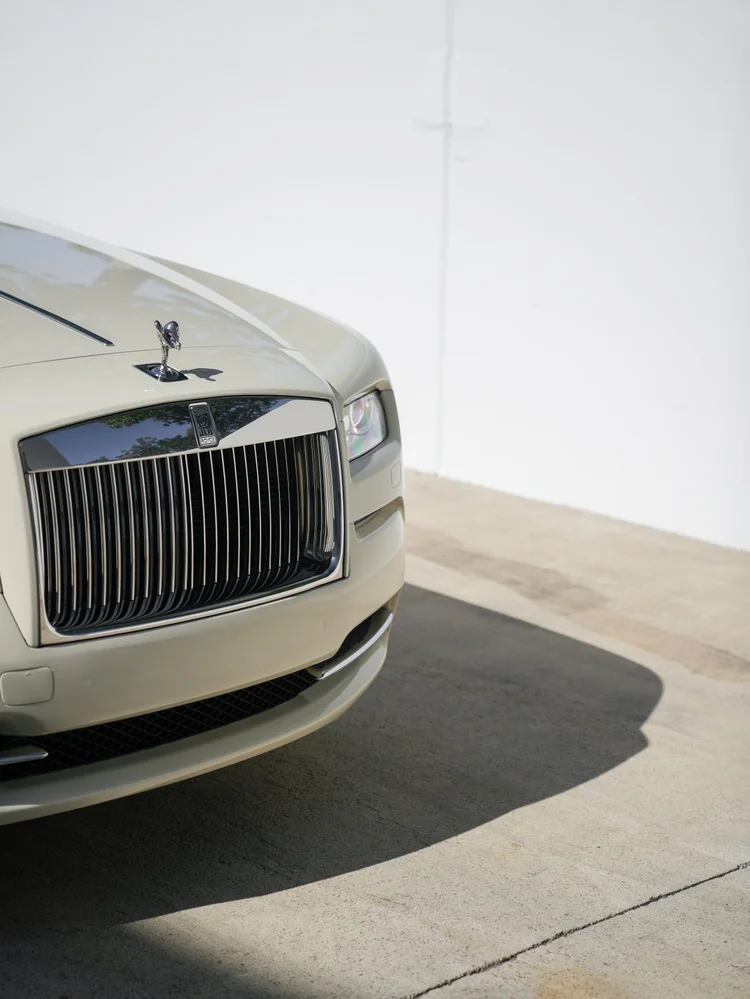 Rolls-Royce Wraith grille and hood ornament with a pale front bumper and one headlamp.