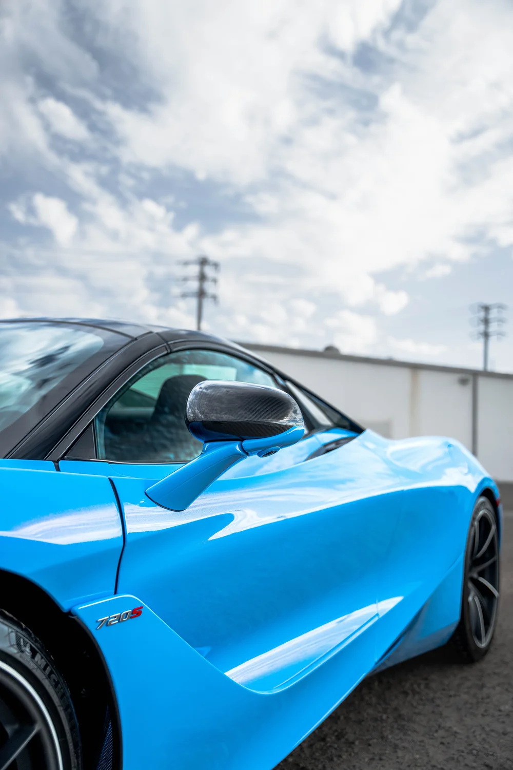 Portrait view of the blue 720S side glass, dark mirror and sculpted door channel