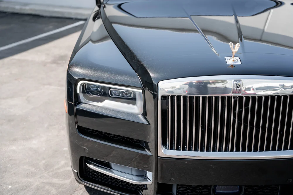 Black Rolls-Royce Cullinan with Chrome Exterior Trim — elevated front detail of the hood, headlamp and bright grille