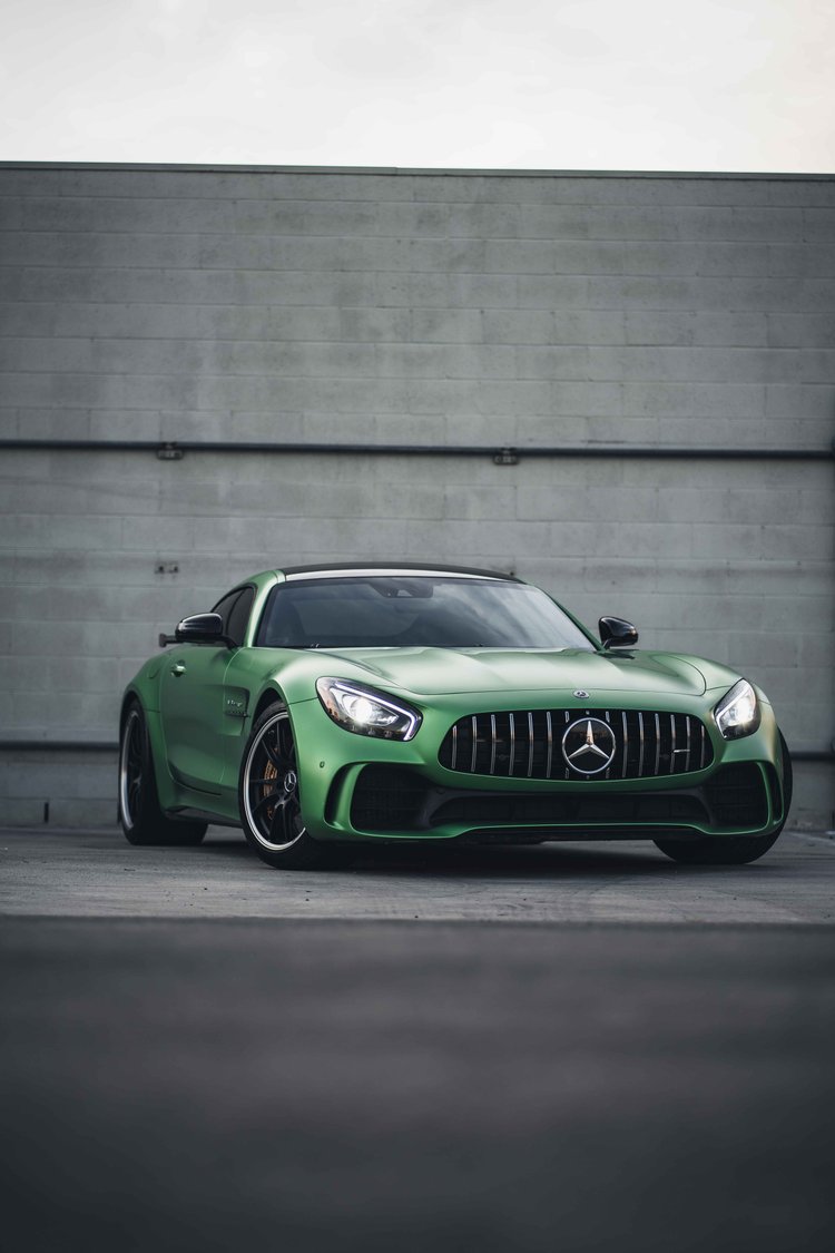 Full green Mercedes-AMG GT R in a tall front three-quarter frame, with the long hood and silver grille star visible.