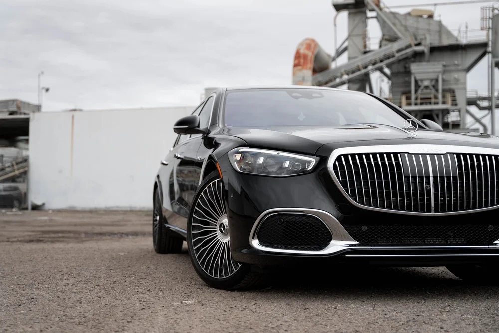 Close front-three-quarter detail of the black Maybach showing a silver multispoke wheel, headlamp and bright grille with the nose cropped at right
