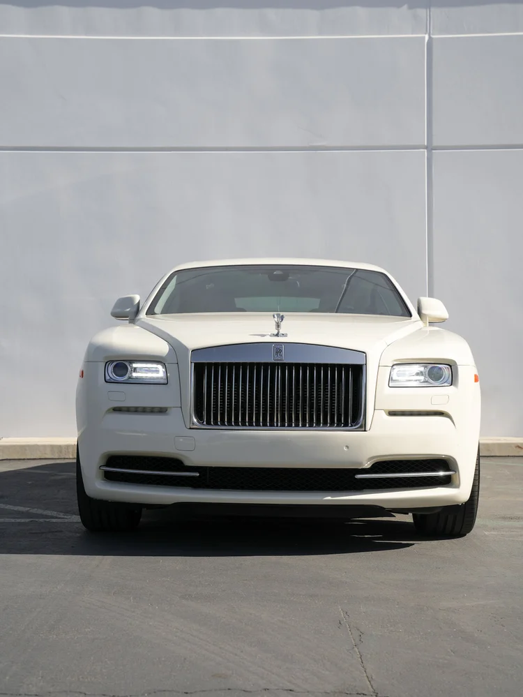 Straight-front view of the pale Rolls-Royce Wraith with chrome grille, both mirrors and front tires.
