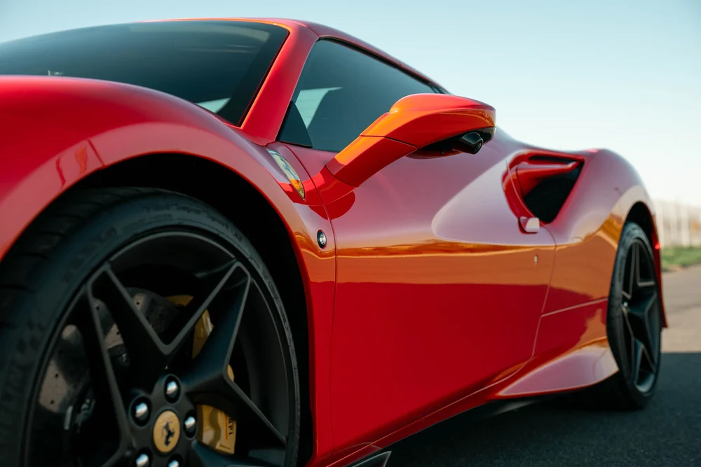 Low side view of the red Ferrari F8 showing red mirror, dark side glass, door and intake