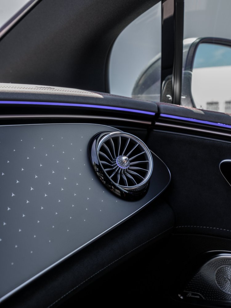 Passenger-side turbine air vent, patterned dashboard trim and purple ambient lighting in the Mercedes-AMG EQE 53.