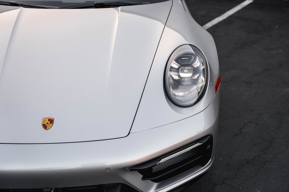 Elevated Targa front-corner detail with round headlight, silver hood and Porsche crest