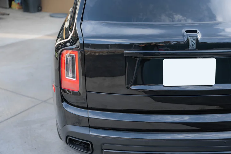 Tailgate and left tail lamp detail with reflections across the black body.