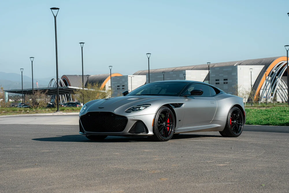 Matte-finish Aston Martin DBS in a front three-quarter view from the other side with black wheels and red calipers
