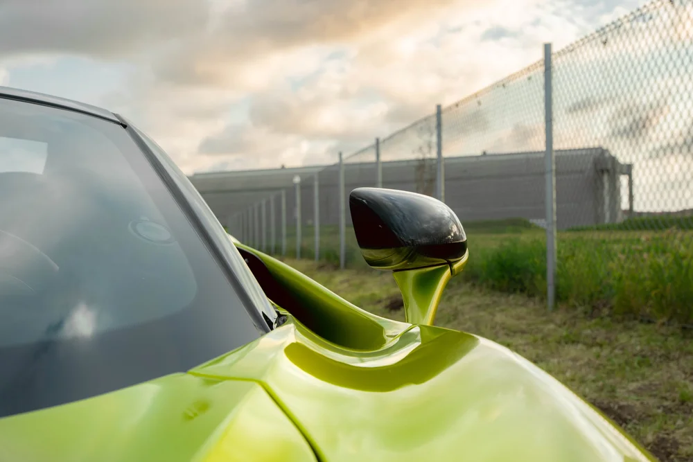Green McLaren 720S mirror housing, windshield border and sculpted green bodywork reflecting the sky