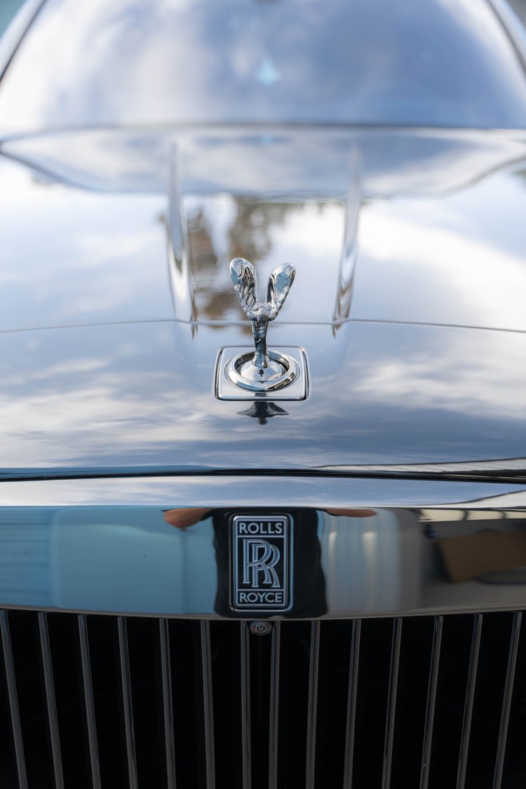 Hood ornament above the RR grille badge with clouds reflected on the hood.