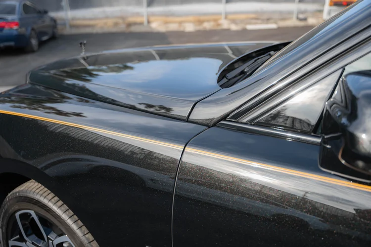 Close view of the front fender, hood and thin yellow body stripe.