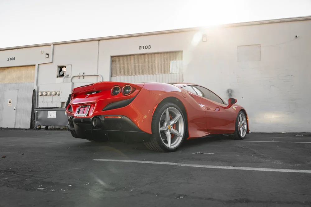 Red Ferrari F8 in a complete low rear three-quarter view with silver wheels and rear diffuser