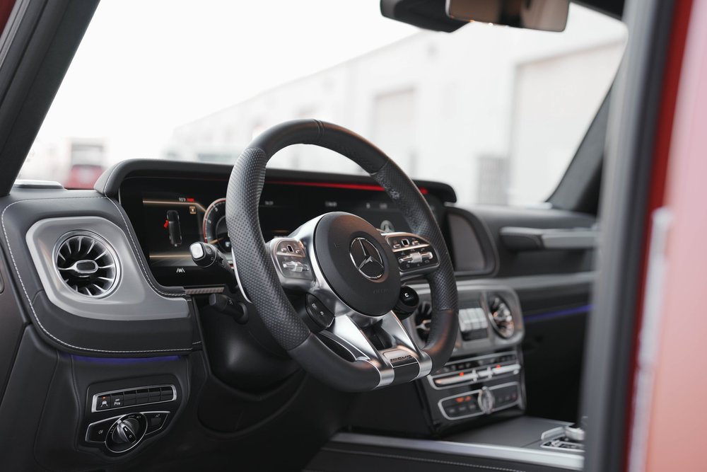 G63 driver cabin with the Mercedes steering-wheel emblem, wide dashboard display, circular vents and center controls