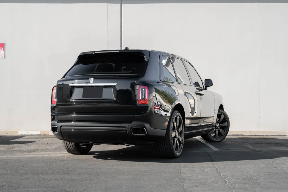 Dark Metallic Grey Rolls-Royce Cullinan — complete rear three-quarter view from a low landscape viewpoint