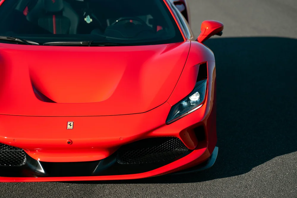 High front-corner view of the red Ferrari F8 showing hood, headlight and windshield