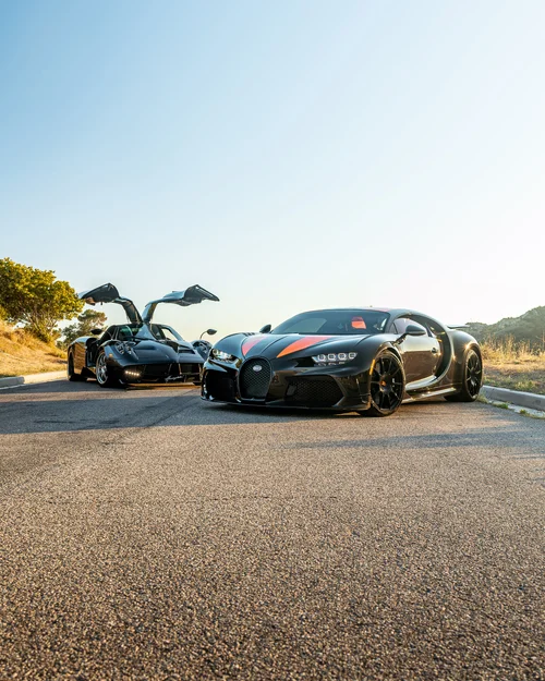 Bugatti Chiron Super Sport 300+ beside a Pagani Huayra with raised doors on a hillside road