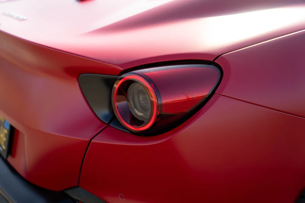 Circular Ferrari Portofino taillamp with red ring, dark surround and adjoining red body seams