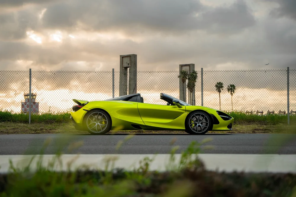 Green McLaren 720S in a complete side profile with both wheels and a raised rear wing visible