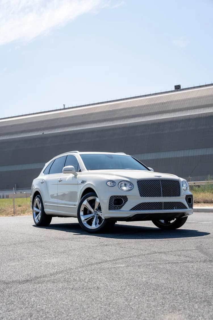 Front corner portrait of the white SUV framed by pavement and sky.