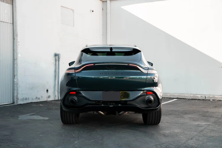 Complete rear view of the green SUV parked on pavement against white walls.