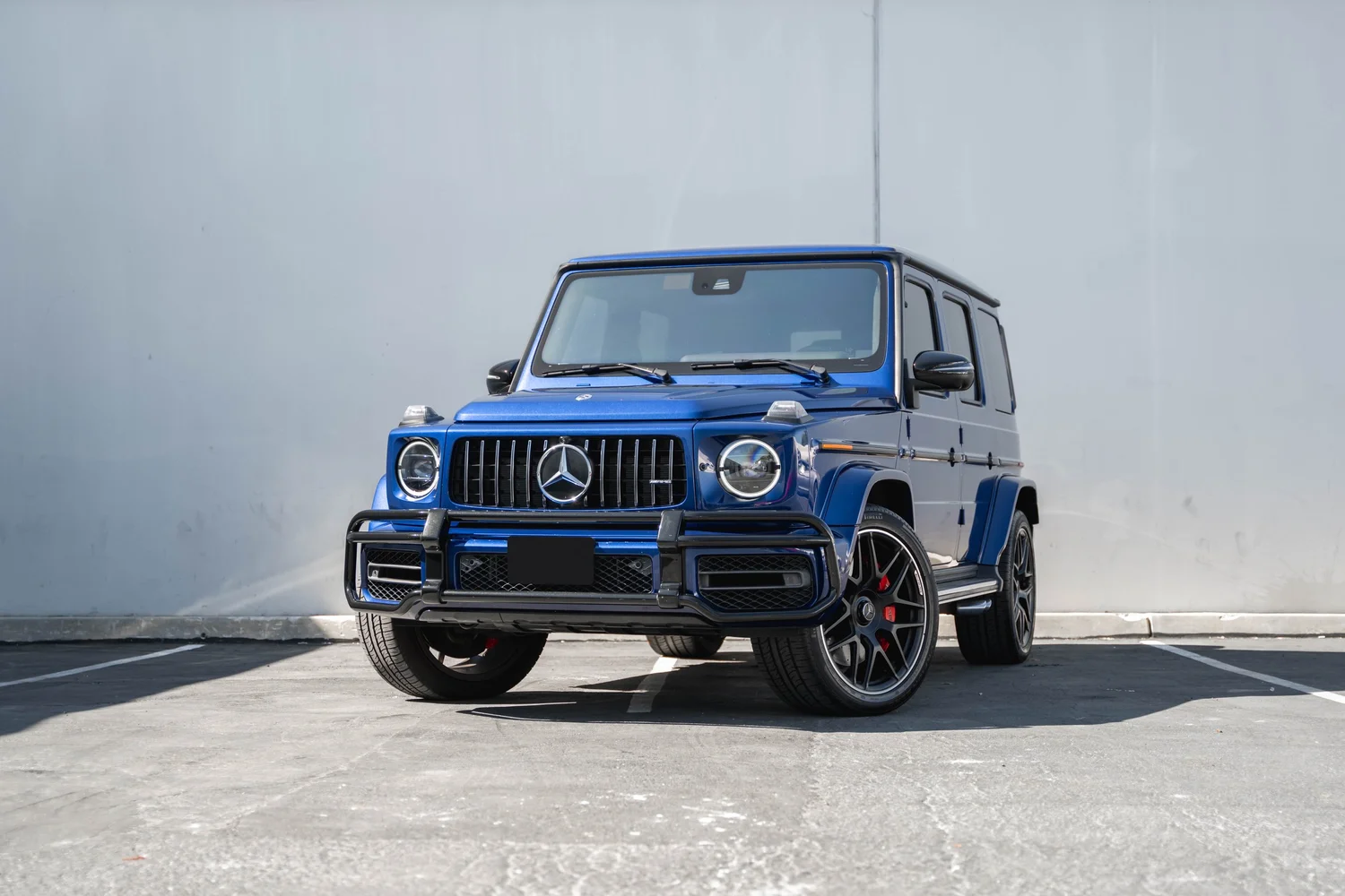 Landscape complete front-three-quarter view of the blue G 63 with dark silver-edged wheels, red calipers and a dark front guard