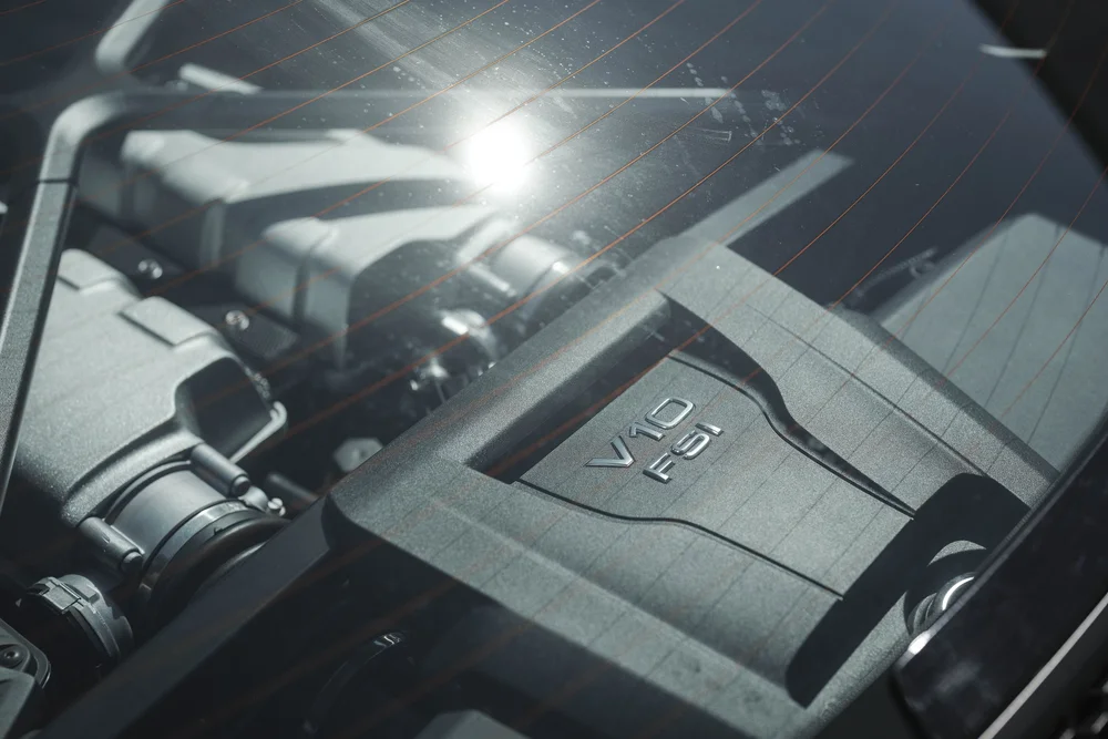Audi R8 engine-cover area visible through rear glass with sunlight reflections