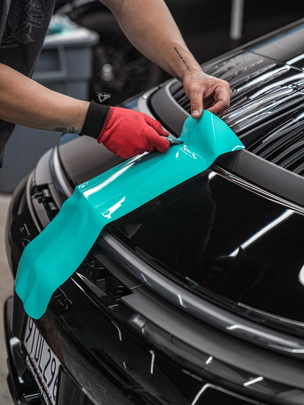 Technician fitting the turquoise custom decal at the Porsche 911 Carrera 4 GTS rear spoiler