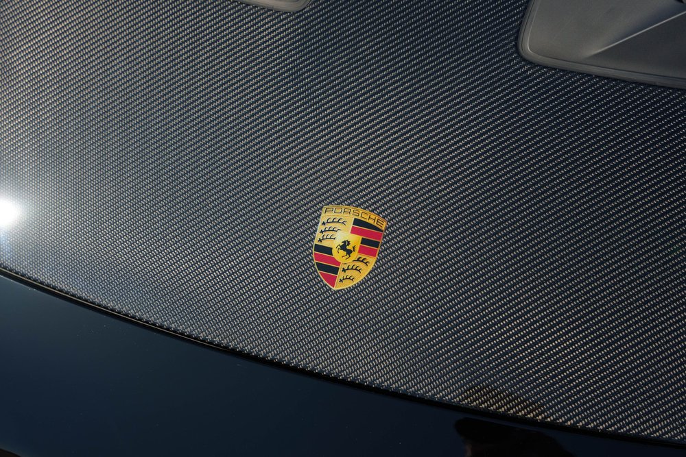 Black Porsche 992.1 GT3 RS, Porsche crest on a woven-pattern hood panel