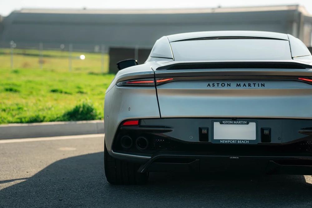 Matte-finish Aston Martin DBS viewed directly from the rear with slim taillights and four round exhaust outlets