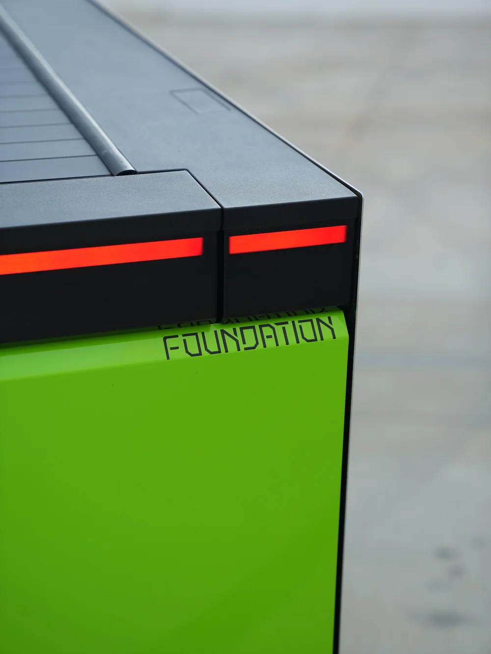 Close rear corner showing the red lamp strip, gray bed-cover surround and FOUNDATION lettering on the green tailgate.