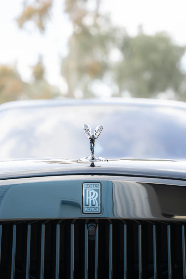Low close-up of the hood ornament and RR badge above the black grille slats.