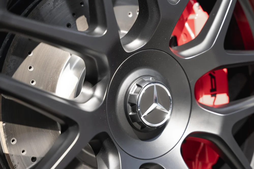 Close view of the Mercedes-star wheel center, dark spokes, red caliper and perforated brake disc