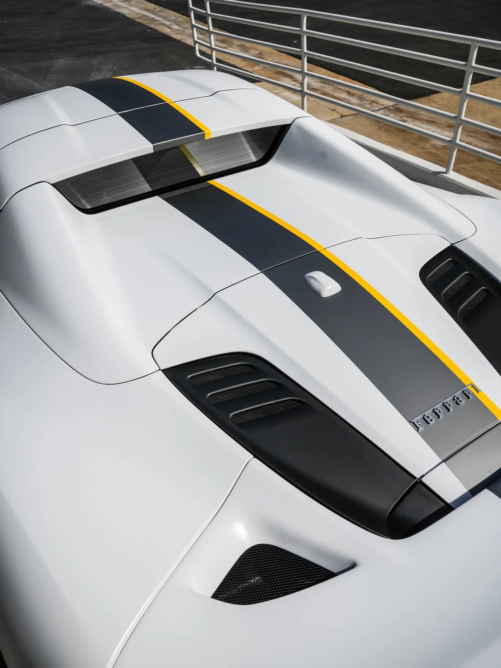 Ferrari F8 Spider rear deck and engine-cover area with a dark livery band and narrow yellow edge