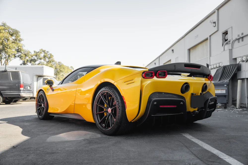Low rear three-quarter view from the other side of the yellow Ferrari SF90 with full body, wheels and rear diffuser visible