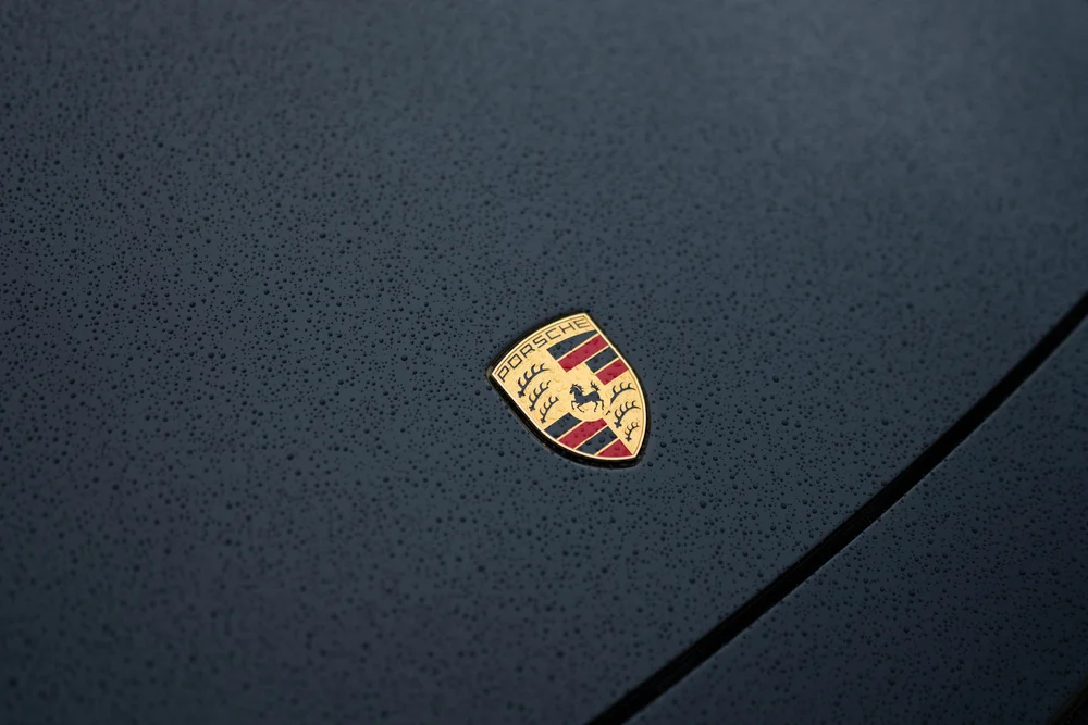 Porsche crest on the black 911 Turbo S hood surrounded by water droplets