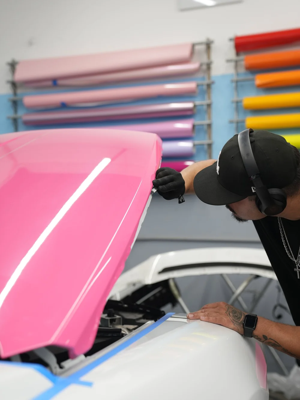 Technician working along the Rose Pink vinyl-covered hood of the Rolls-Royce Wraith
