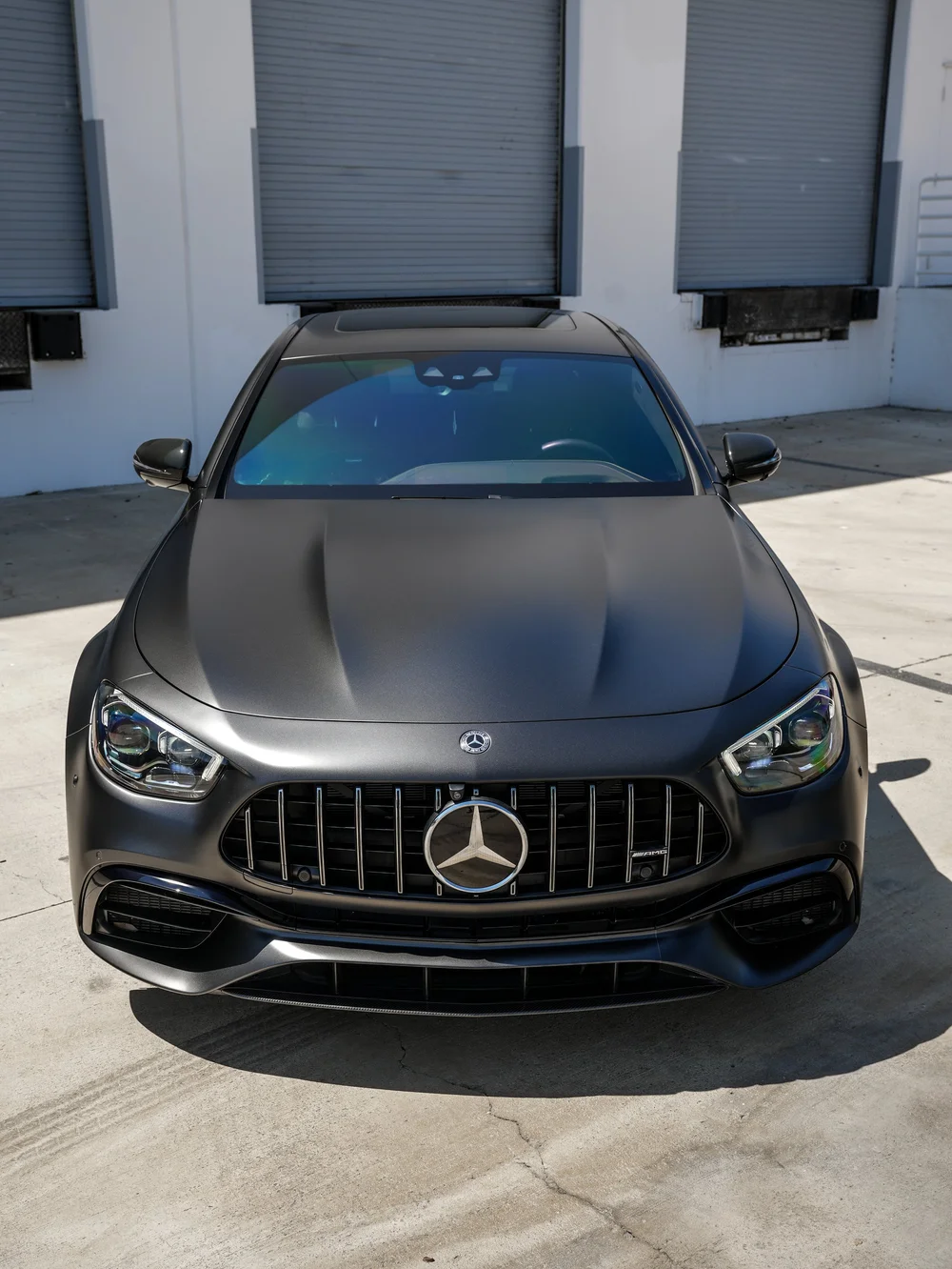 Elevated straight-front view of the Mercedes-AMG E 63 S showing its matte-looking hood, star-centered vertical grille, headlamps, mirrors and windshield.