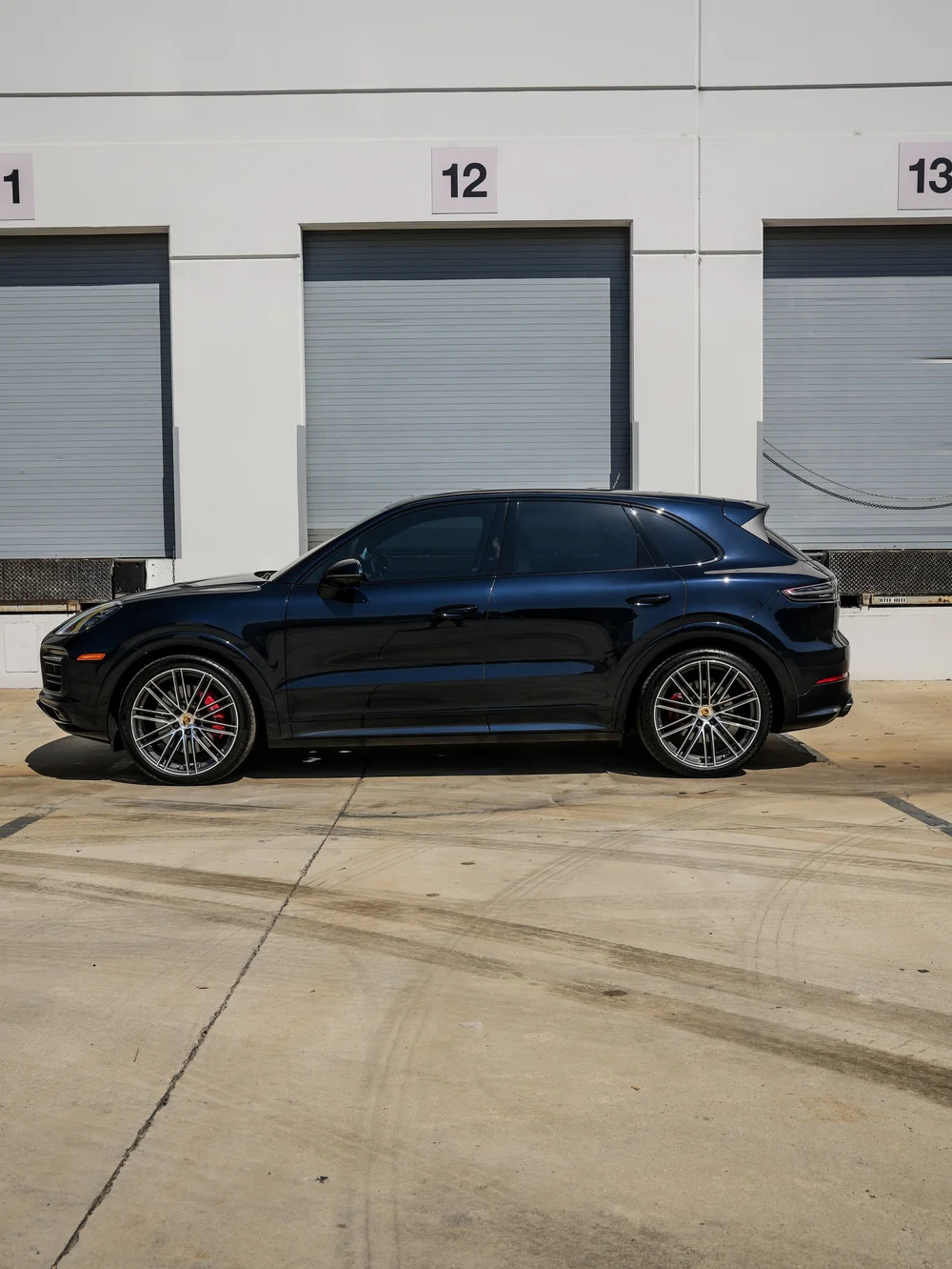 Complete left-facing side profile of the dark blue Porsche Cayenne GTS with silver multi-spoke wheels, red calipers and dark side glass.