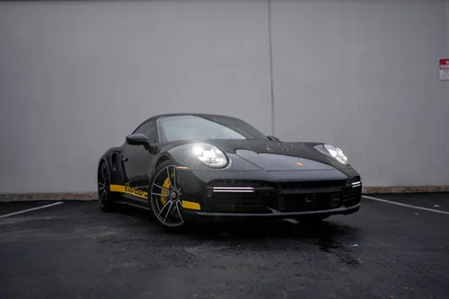 Black Porsche 911 Turbo S with yellow side decal, front three-quarter view