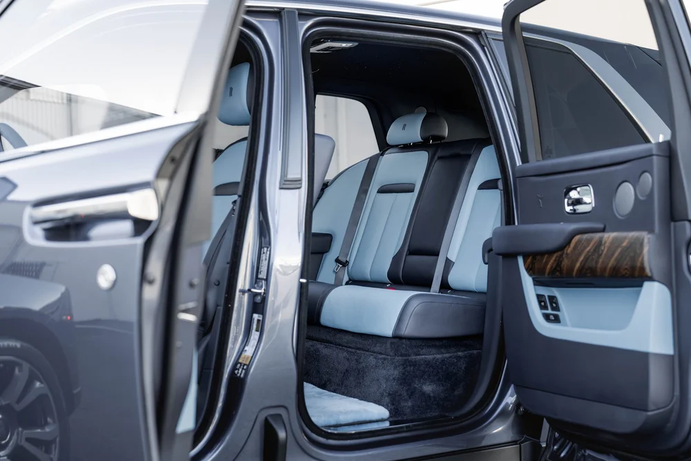 Dark Blue Rolls-Royce Cullinan — blue rear seating and door trim viewed through the open rear doorway